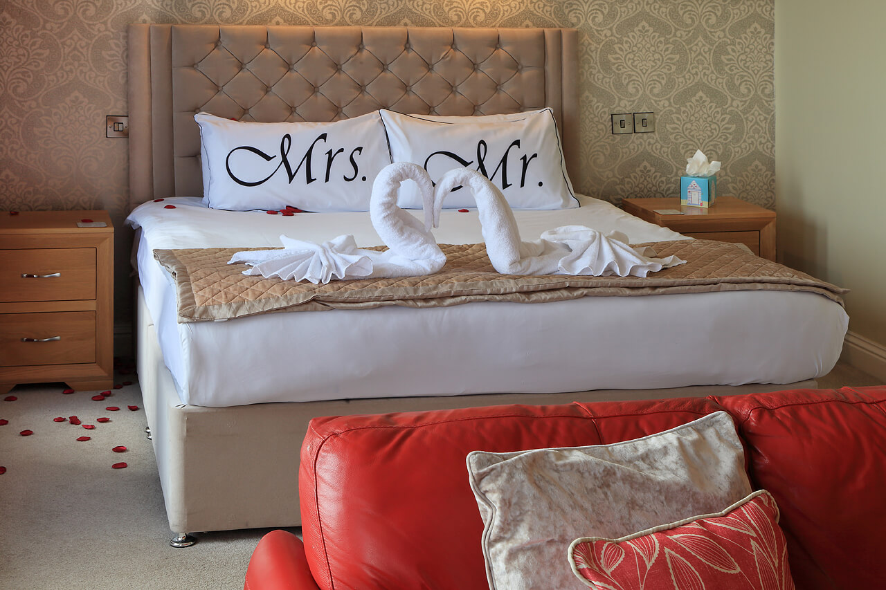 Bridal suite with four poster bed, featuring a bottle of prosecco and scattered rose petals